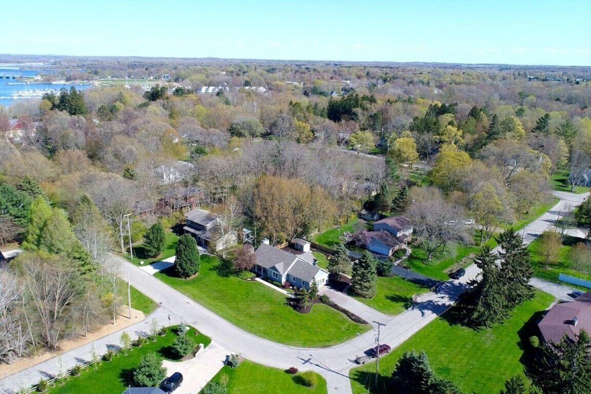 An aerial view of a residential area with houses, roads, and a river in the background.