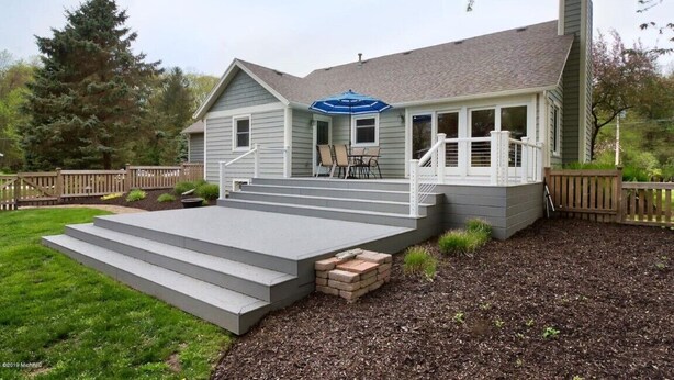 A two-story house with a covered porch, a chimney, and a small deck with steps leading up to the entrance. - Secluded Cottage Getaway (Saugatuck)