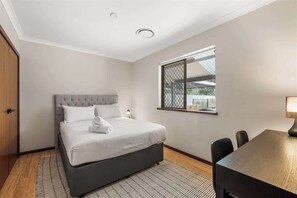 A bedroom with a bed, a desk, and a window with a view. - Prowse Beach House—Family Fun & Ocean Adventures (Dunsborough)