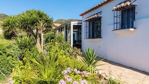 Un edificio bianco con tetto in tegole e un giardino con diverse piante e fiori.