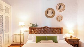 Una camera da letto ordinata con una testiera in legno, due lampade ai comodini e un termosifone.