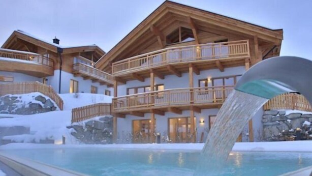 Ein Hotel mit Poolbereich, Holzbalkonen und verschneiter Umgebung.