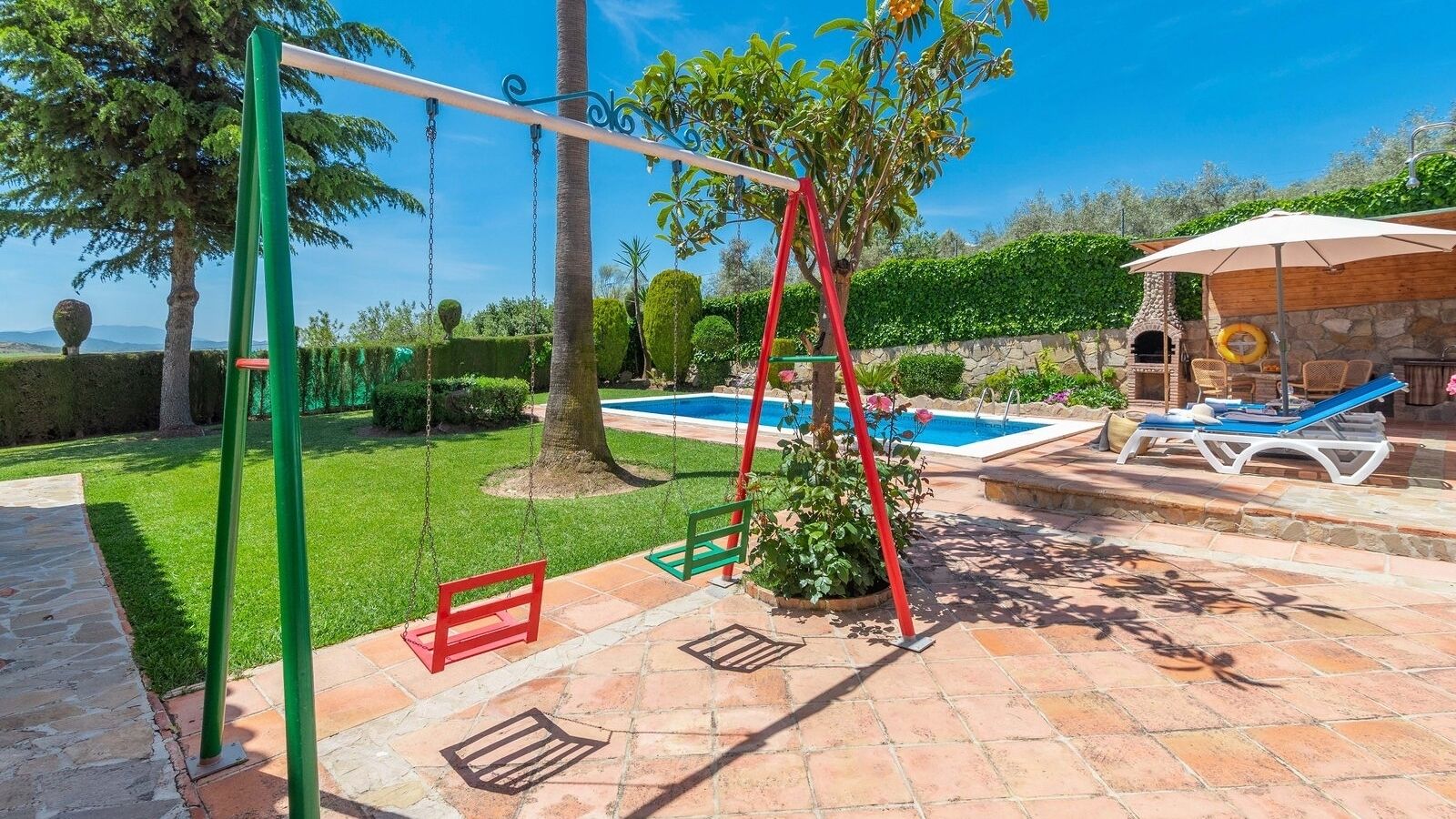 A patio with a swing set, a pool, and outdoor seating.