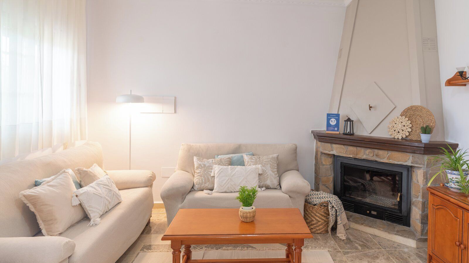 A living room with a sofa, a coffee table, a fireplace, and a lamp.