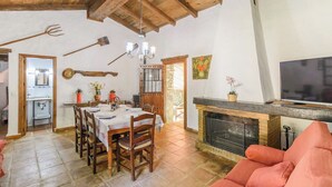 A dining area with a wooden table set for six, a fireplace, and a television on a stone mantel. - Molino La Catedral Grazalema by Ruralidays (Cádiz)