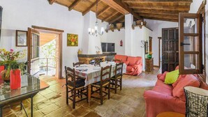 A dining area with a wooden table and chairs, a red sofa, and a chandelier. - Molino La Catedral Grazalema by Ruralidays (Cádiz)