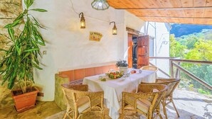 A dining area with wicker chairs, a table set with a white tablecloth, a potted plant, and a sign reading "LA MAQUILA". - Molino La Catedral Grazalema by Ruralidays (Cádiz)