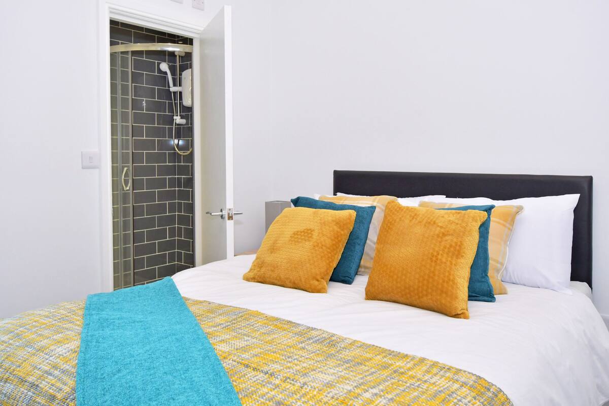A hotel room with a bed, a shower, and a tiled wall.