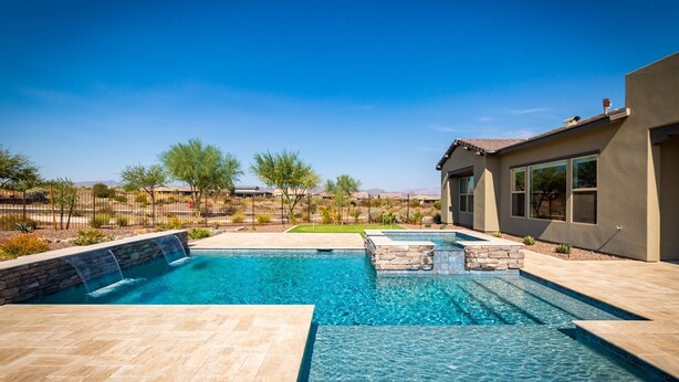 A swimming pool with a waterfall feature, surrounded by a landscaped garden and a house. - Rio Verde Home with Stunning Views and a Private Pool (Rio Verde)