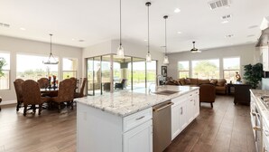 A spacious kitchen with a central island, white cabinetry, and a dining area with patterned chairs. - Rio Verde Home with Stunning Views and a Private Pool (Rio Verde)