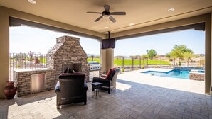 A covered patio with a stone fireplace, outdoor seating, and a view of a swimming pool. - Rio Verde Home with Stunning Views and a Private Pool (Rio Verde)