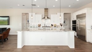 A spacious kitchen with white cabinetry, a large island with a sink, and stainless steel appliances. - Rio Verde Home with Stunning Views and a Private Pool (Rio Verde)