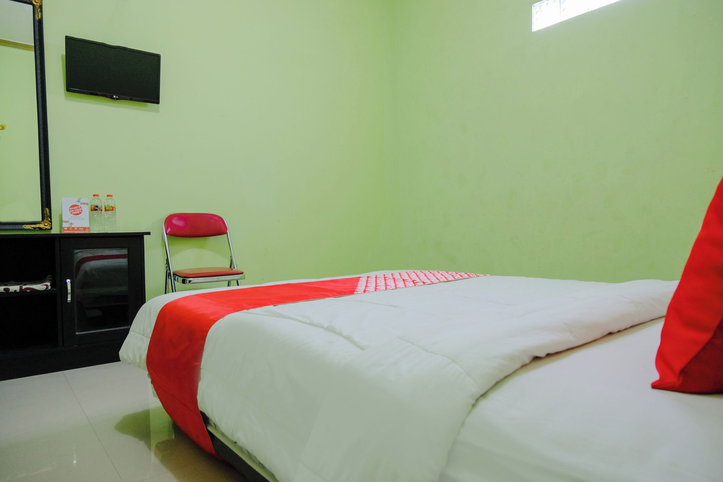 Una habitación con una cama, una silla, un escritorio y un televisor de pantalla plana en la pared.