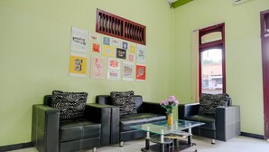 A waiting area with three black leather sofas, a glass coffee table, and motivational posters on the wall. - Oyo 2508 Alba Suites Homestay (Tulungagung)