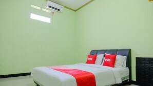 A neatly made bed with a red and white bedspread and two red pillows with the word "OYO" on them. - Oyo 2508 Alba Suites Homestay (Tulungagung)