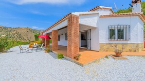 A house with a patio, outdoor seating, and a view of a hilly landscape. - Villa Soleada Algarrobo by Ruralidays (Málaga)