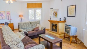 A cozy living room with a sofa, armchairs, a coffee table, a fireplace, and a television on a stand. - Villa Soleada Algarrobo by Ruralidays (Málaga)