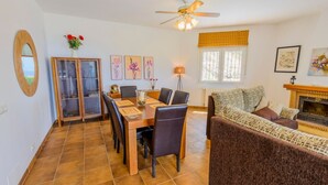 A dining area with a wooden table and chairs, a sofa, and a fireplace. - Villa Soleada Algarrobo by Ruralidays (Málaga)