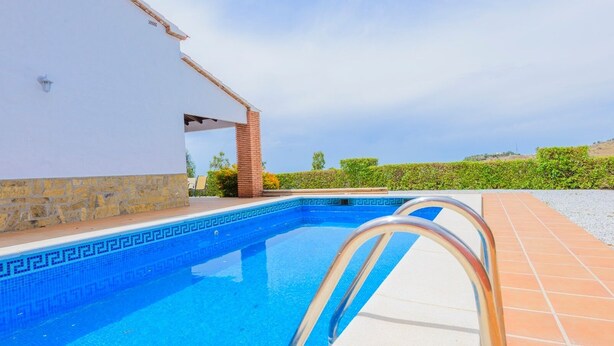 A swimming pool with a white building and a brick structure in the background. - Villa Soleada Algarrobo by Ruralidays (Málaga)