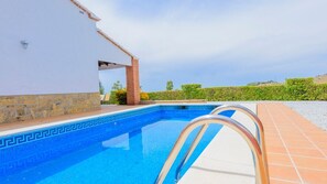 A swimming pool with a white building and a brick structure in the background. - Villa Soleada Algarrobo by Ruralidays (Málaga)