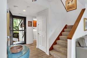 A hallway with a wooden staircase, a white door, and a glass door leading outside. - Beachside Hilton Head Villa with Pool, Tennis (Hilton Head Island)