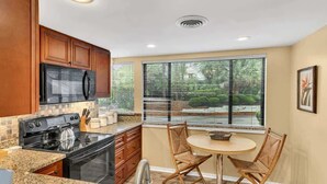 A kitchen with wooden cabinets, a black stove, and a dining area with a round table and two chairs.