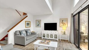 A modern living room with a grey sofa, white coffee table, and a flat-screen TV.