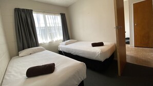 A hotel room with two beds, a window with curtains, and a door leading to another room. - Ulster Apartments (Hamilton)