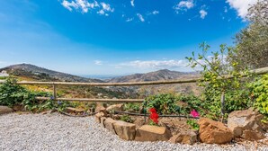 Un espacio al aire libre pintoresco con un sendero de grava, una valla de madera y vistas a colinas distantes.