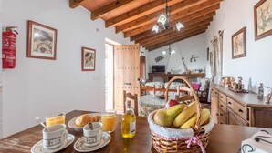 Una mesa de desayuno con cruasanes, zumo de naranja y una botella de aceite de oliva.