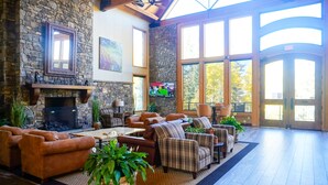 A spacious living room with a stone fireplace, comfortable seating, and large windows allowing natural light. - Telluride - 1 Bedroom with Forest View (Telluride)