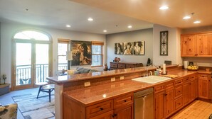 A spacious kitchen with wooden cabinets, a large island, and a built-in dishwasher. - Telluride - 1 Bedroom with Forest View (Telluride)