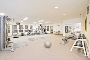 A spacious gym with various exercise equipment, including treadmills, stationary bikes, and free weights.
