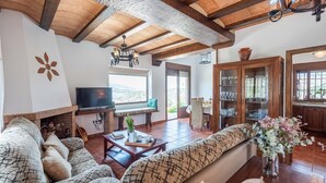 Uma sala de estar ampla com lareira, televisão e área de jantar com um armário de madeira.