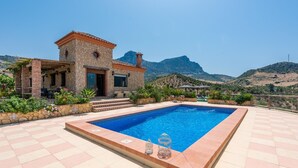 Um edifício de pedra com piscina e vista para as montanhas.