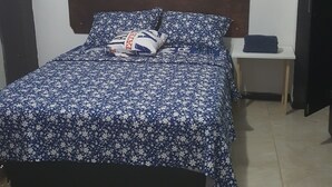 Una camera da letto con un letto, un comodino, un quadro appeso e una porta.