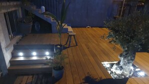 Une terrasse en bois avec un escalier, des plantes en pot et une petite table.