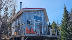 Een houten chalet met een balkon, schoorsteen en terras.