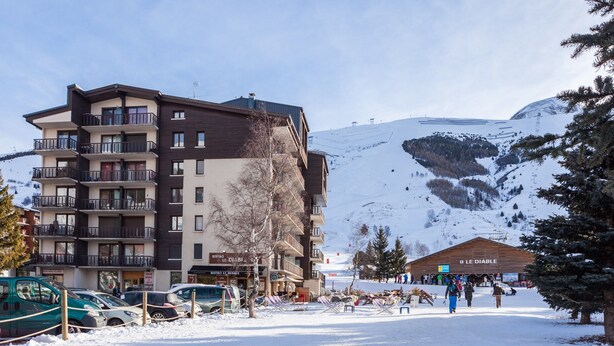 A multi-story hotel with balconies, a ski resort in the background, and a sign for "Le Diable."