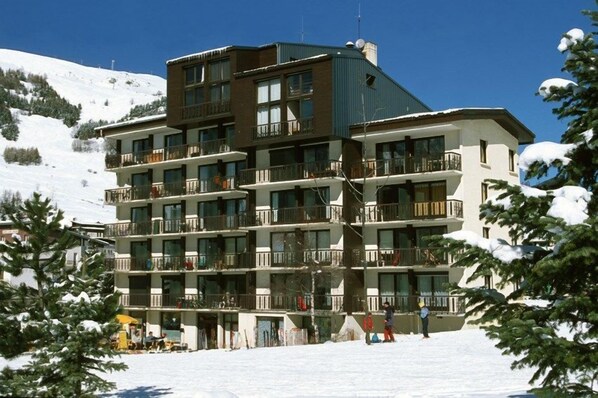 A multi-story hotel with balconies, located in a snowy mountainous area.