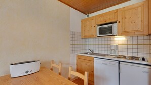 A compact kitchen with wooden cabinets, a microwave, a sink, and a dishwasher.