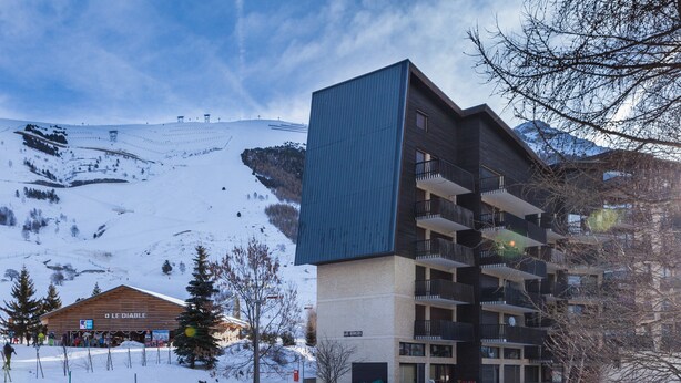 A modern building with a ski resort in the background.