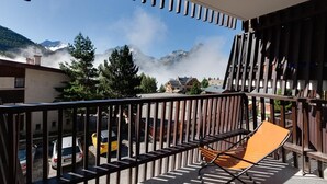A balcony with a view of mountains and a parked car.