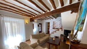 A spacious living room with a sofa set, a wooden staircase, and a television.