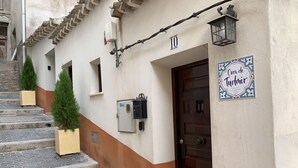 A building with a brown and white facade, a wooden door, and a sign reading "Cora de Tudmir."