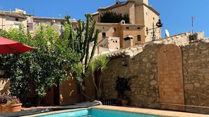 A swimming pool with a stone wall and a building with a tower in the background.