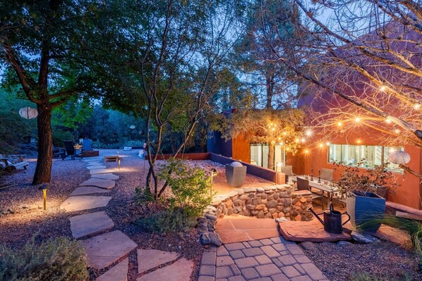 A well-lit outdoor patio area with stone pathways, seating, and a stone wall.