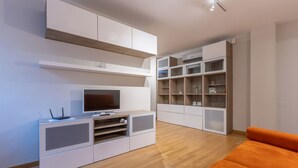 Una sala de estar moderna con sistemas de entretenimiento integrados, un sofá y unidades de almacenaje.