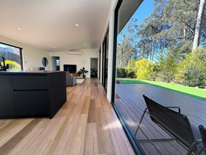 A modern interior with a kitchen, dining area, and a view of a landscaped garden.