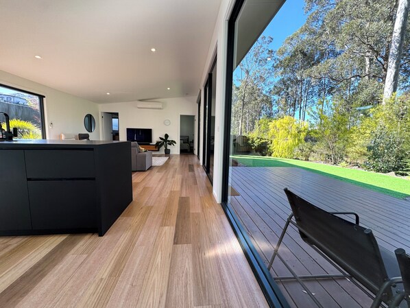 A modern interior with a kitchen, dining area, and a view of a landscaped garden.